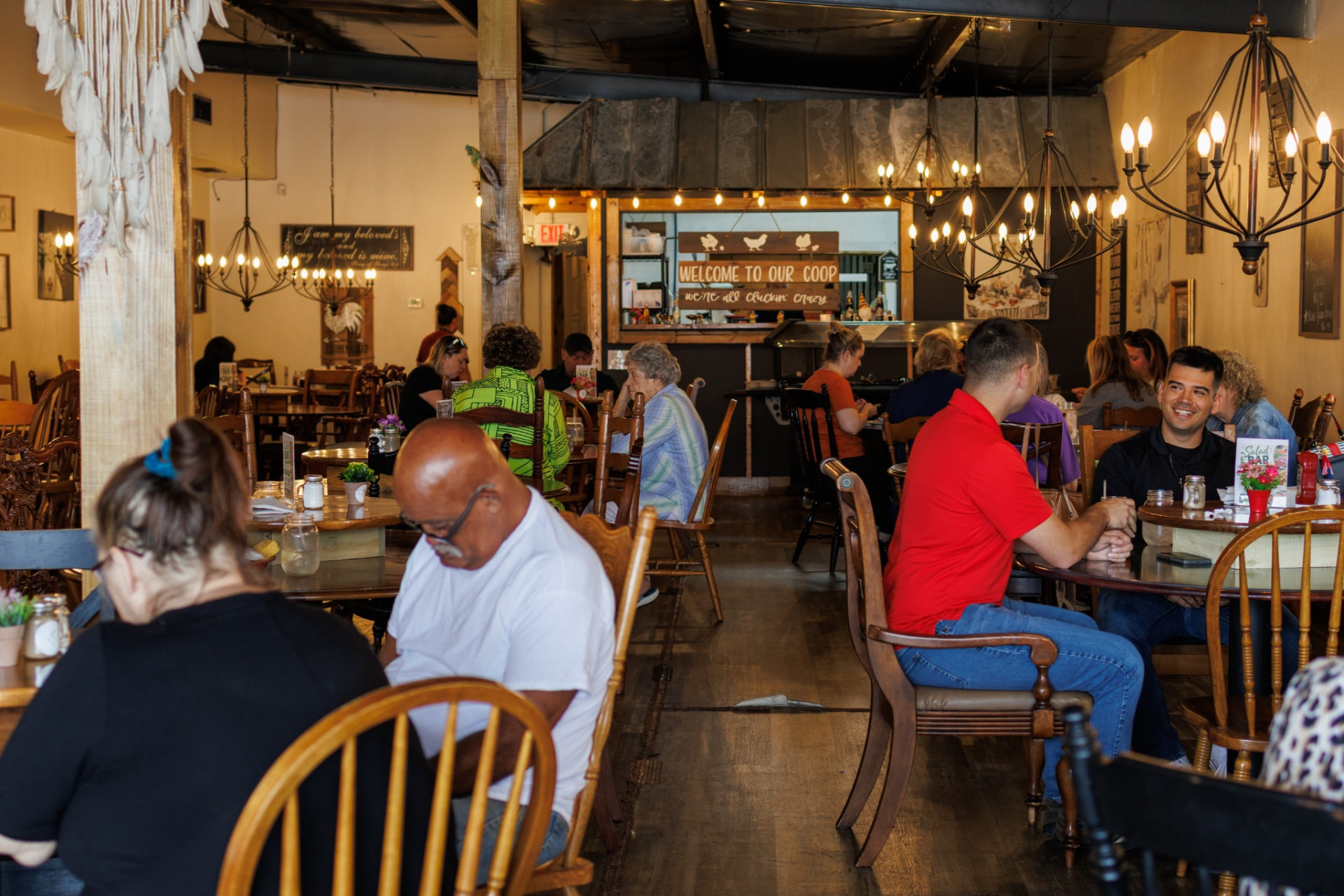 A busy dining room full of friends and families beneath the Welcome to Our Coop sign at Brown Chicken Brown Cow