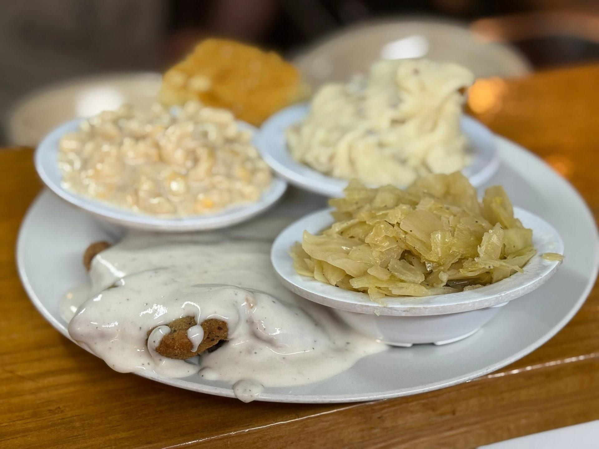 A meat & three plate — country fried steak smothered in white gravy with cabbage, mashed potatoes and creamed corn