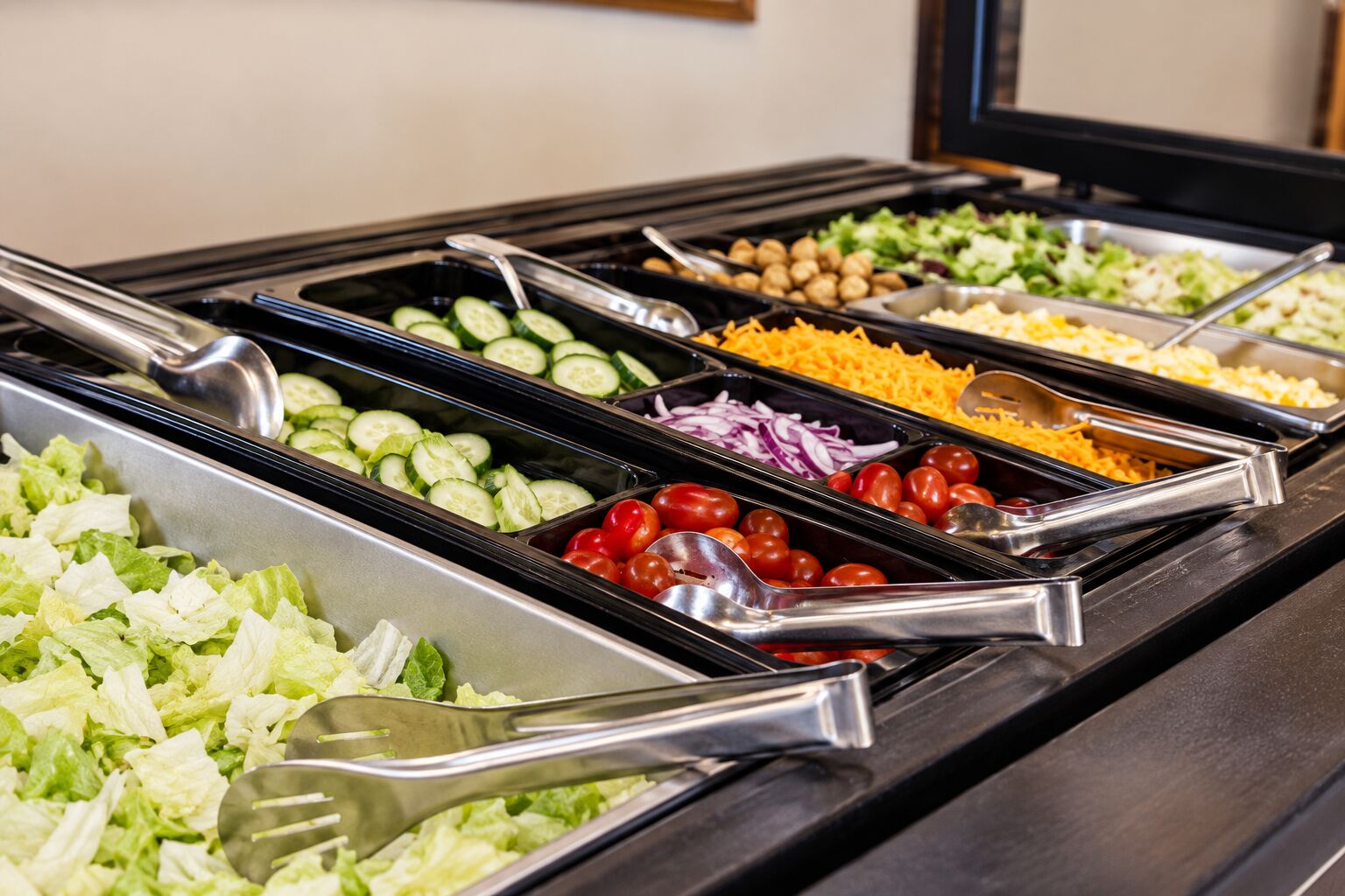 Fresh salad bar with lettuce, cucumbers, tomatoes, cheese, and toppings at Brown Chicken Brown Cow